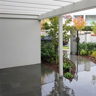  Inner suburban garden, random rectangular paving entrance with wrought iron fence and gates.  Planted as too soften building lines.